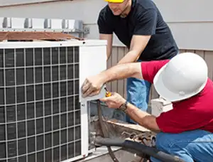 HVAC technicians repairing an outdoor AC unit on a rooftop in Greensboro, NC